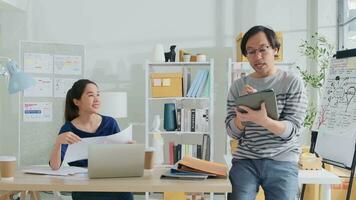 dois jovem ásia comece companhia parceiros discutir e chuva de ideias dentro casual pequeno o negócio escritório, marketing planejamento empregos em uma computador portátil, e freelance trabalhos Como comércio eletrônico empreendedor e colega de trabalho equipe. video