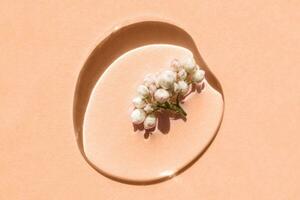 A drop of cosmetic gel with flower on a Peach Fuzz background. photo