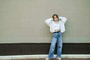 Portrait of a teenage girl in headphones against a gray wall. photo