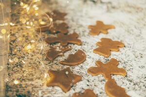 Making Christmas cookies. Figured gingerbread cookies on the kitchen table with holiday lights photo