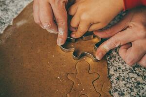 un mamá y su hijo contratar en el encantador tarea de preparando Navidad pan de jengibre foto