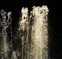 agua fuente chapoteo en un negro antecedentes foto