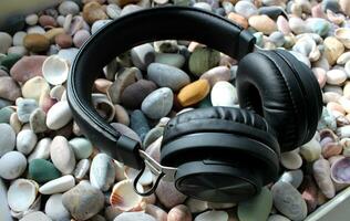 Wireless Headphones On A Smooth Sea Rocks And Shells Angle View photo