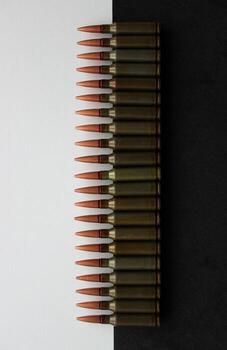 A row of live ammunition half lying on a black surface and half on a white surface stock photo for vertical story