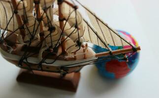 Closeup Top View Of Wooden Masted Ship Model And Blurred Globe Behind Bowsprit photo