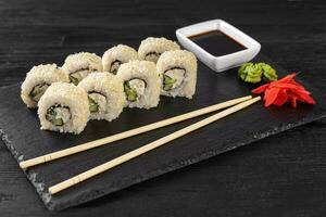 Sushi roll Philadelphia with salmon, sesame seeds, avocado, cream cheese on black slate background photo