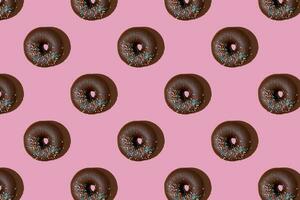 Chocolate donuts pattern on pink background. Top view, flat lay photo