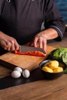 Close-up of dressed in black chef cuts with knife the salmon at the professional kitchen. photo