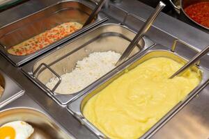 Fast food bistro, food in metal trays, cutlet salads garnish on the cafe window photo