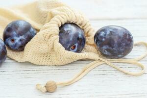 Reusable eco shopping bags with plums, replacing plastic bags photo