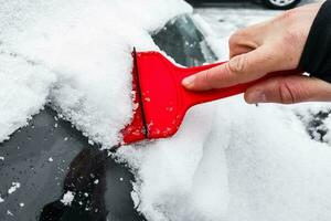 limpieza el coche desde nieve con un raspador foto