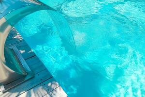 Waterfall in the swimming pool with blue water in the background photo