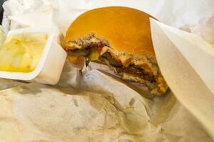 mordido hamburguesa con queso con chuleta y pepinos de cerca. foto