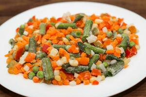 Frozen vegetables carrots, peas, beans in a plate photo