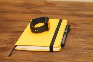 A black technological smart watch lies on a notepad for time management. photo