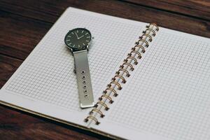 Open notebook diary with clock with black dial, time management concept. photo