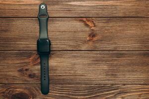 A black technological smart watch lies on a wooden background. photo