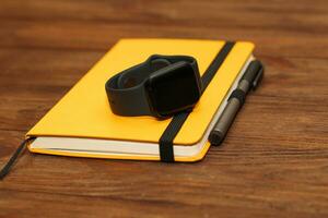 A black technological smart watch lies on a notepad for time management. photo
