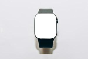 A black technological smart watch lies on a wooden background with a white screen for text space. photo