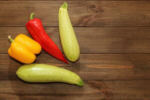 Red pepper Kapi with yellow sweet pepper and zucchini on a wooden background, space for text. photo