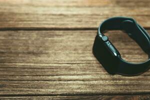 A black technological smart watch lies on a wooden background photo