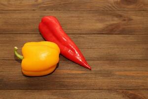 Red pepper Kapi with yellow sweet pepper on a wooden background, space for text. photo