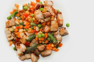 Stewed vegetables with meat, vegetables carrots, peas, beans in a plate. photo