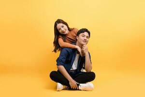 Two good looking Asian couples sit and relax on yellow background. photo
