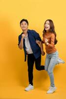 Happy smiling Asian couple with surprise isolated on yellow studio background. photo