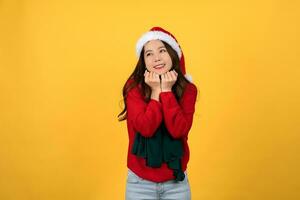 Photo of an excited beautiful Asian woman wearing a Christmas themed outfit with some expectant expressions on a yellow background.