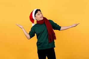 Surprised handsome Asian man wearing Christmas themed clothes on isolated gray background. photo