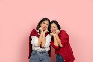 Attractive Asian female friend smiling at camera. Beautiful girl in a stylish shirt poses cheerfully on a pink background. photo