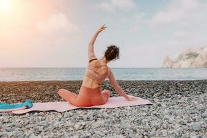 mujer mar pilates deportivo contento medio Envejecido mujer practicando aptitud en playa cerca mar, sonriente activo hembra formación con anillo en yoga estera afuera, disfrutando sano estilo de vida, armonía y meditación foto