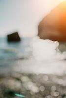 resumen naturaleza verano Oceano puesta de sol mar antecedentes. pequeño olas en agua superficie en movimiento difuminar con bokeh luces desde amanecer. día festivo, vacaciones y recreativo antecedentes concepto. foto