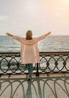 Woman summer travel sea. Happy tourist enjoy taking picture outdoors for memories. Carefree woman traveler posing on beach at sea on sunset, sharing travel adventure journey. Holiday vacation concept. photo