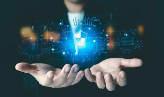 A businessman is displaying a 3D hologram concept of the Network Security on his hand. He is wearing a business suit and standing against a black background of a futuristic technology screen. photo