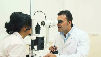 un experimentado médico mira a el dispositivo para pruebas el pacientes visión video