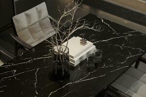 Dried stem into a pot with books and glass displayed on the table. photo