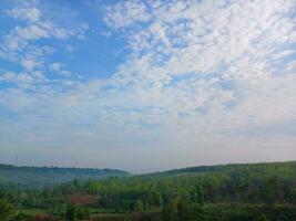 The view of the plantations is green and beautiful, there are blue clouds. See the view of the hills with blue clouds. photo