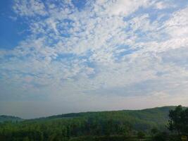 The view of the plantations is green and beautiful, there are blue clouds. See the view of the hills with blue clouds. photo