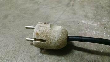 Electric plug on workshop floor. Electric European plug. White power cable with plug. Power cord close-up. photo