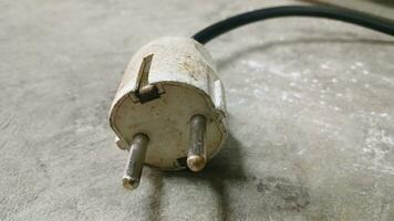 Electric plug on workshop floor. Electric European plug. White power cable with plug. Power cord close-up. photo