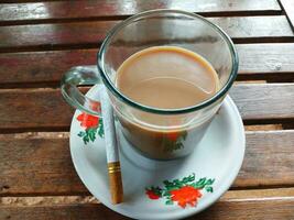 taza de café y un filtrar cigarrillo en un oscuro de madera mesa antecedentes. foto