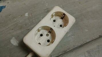 Old electrical socket isolated on gray work floor. Industrial work requires electrical power. Isolation of sockets on work floor is dull. photo