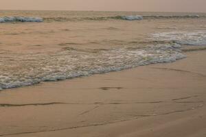 foam of sea or ocean waves against the backdrop of the setting sun photo