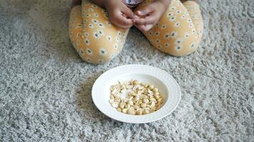 child hand pick peanuts in a bowl on table video