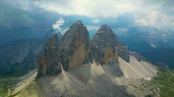 antenn se av Tre cime di lavaredo berg under en molnig dag med få Sol öppningar i de dolomiterna, Italien. dramatisk och filmiska landskap. mycket känd platser för vandring och sten klättrande. video