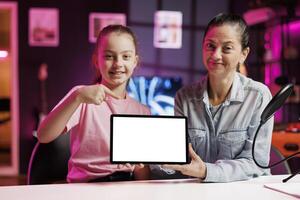 Daughter and mother being sponsored by partnering brand to do mockup tablet unboxing content. Little kid and parent do influencer marketing, doing isolated screen device product placement photo