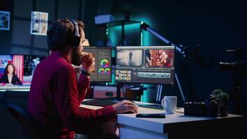 Video editor receiving phone call while arranging recorded stock clips into seamless whole in creative media studio. Videographer talking with director on smartphone while assembling recorded footage