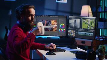 vidéo éditeur corriger défectueux images, classement et coloration, profiter tasse de café dans Créatif studio. vidéaste ajouter spécial effets à clips, en buvant chaud boisson dans médias entreprise Bureau video